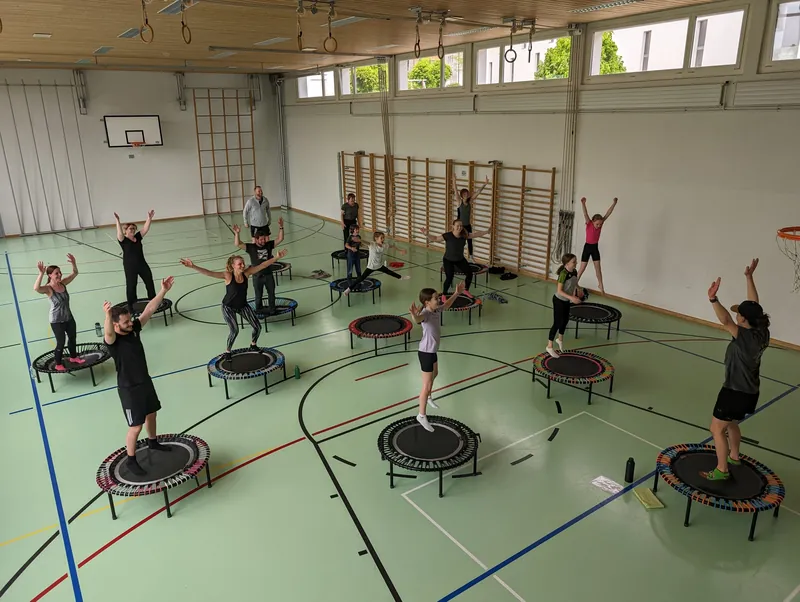 Eine Trampolin-Fitnessgruppe in der Turnhalle beim Coop Gemeindeduell 2024.