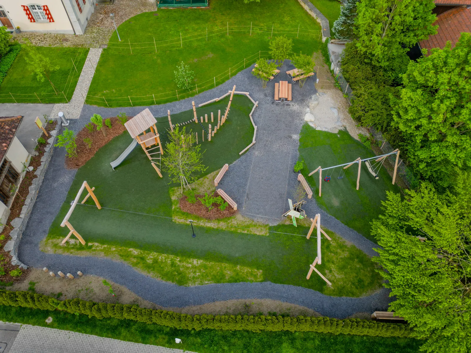 Der fertige Generationenpark von oben: geschwungene Wege, Spielgeräte und frisches Grün auf der Pfarrwiese.